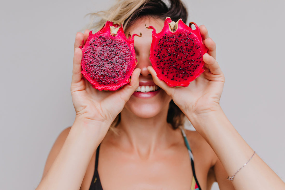 woman holding pink dragon fruit